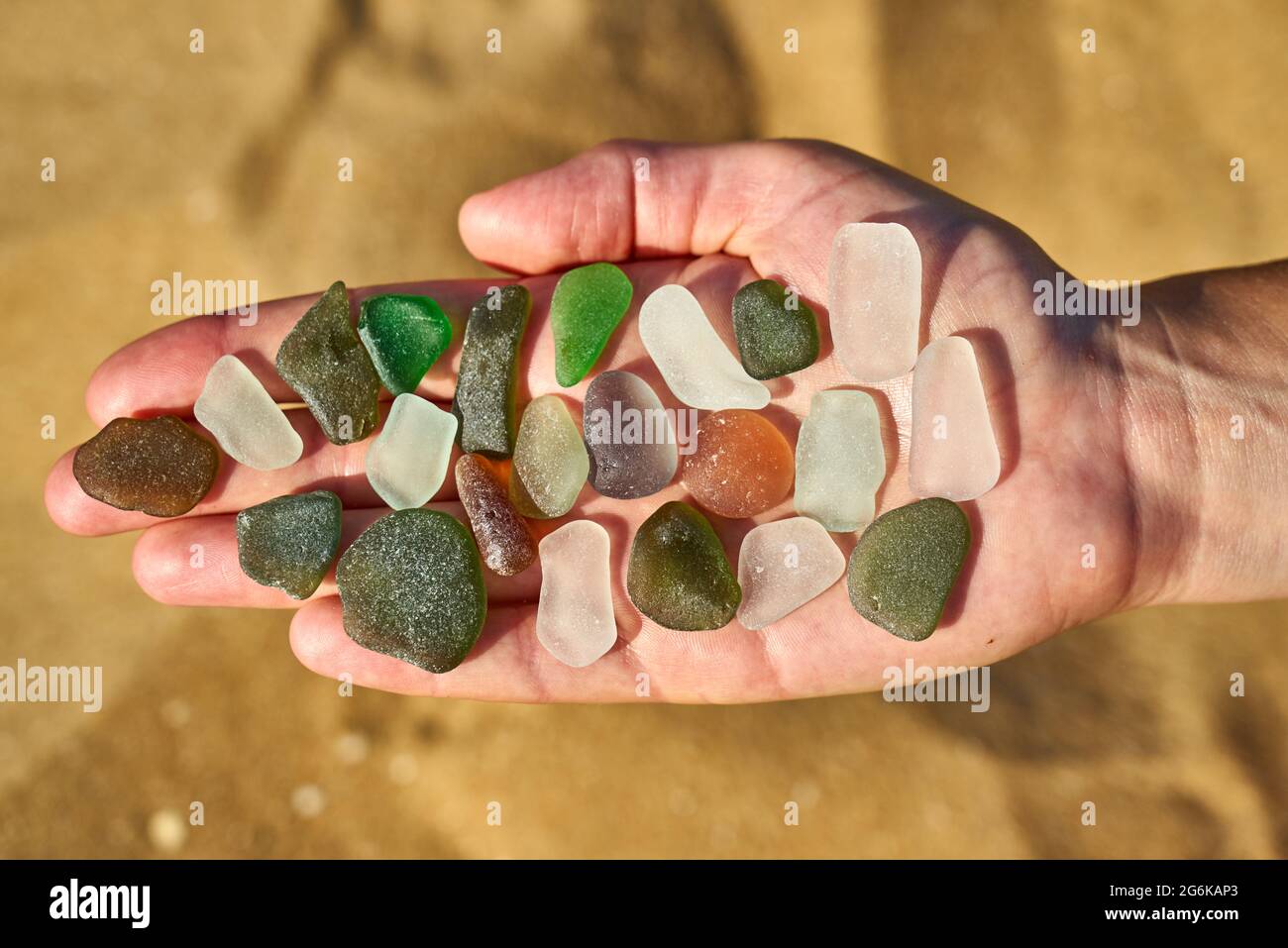 Pezzi di vetro marino sono disposti su una mano aperta Foto Stock