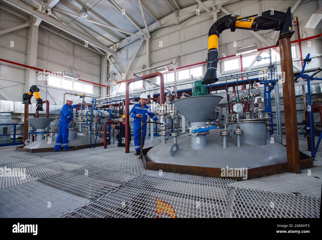 Atyrau, Kazakistan-Maggio 21,2012: Impianto chimico Rauan Nalco. Tre operatori che regolano il braccio dell'estrattore di fumi (collettore di polveri) con la cappa. Tramoggia in metallo grigio (f Foto Stock