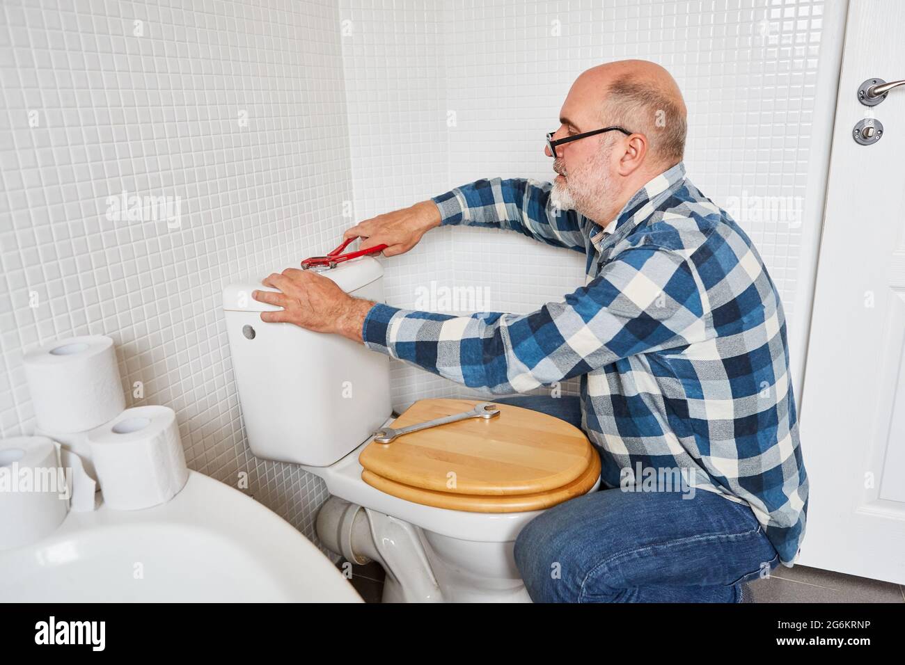 L'artigiano idraulico assembla la cisterna della toilette o ripara un filo difettoso Foto Stock