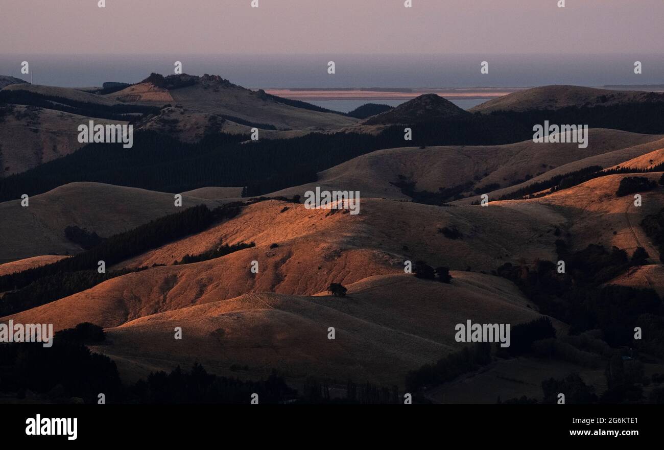 Alba su Porthills, Christchurch, Aotearoa Nuova Zelanda. Le Port Hills sono un residuo di 12 milioni di anni del cratere del vulcano Lyttelton. Vento, ra Foto Stock