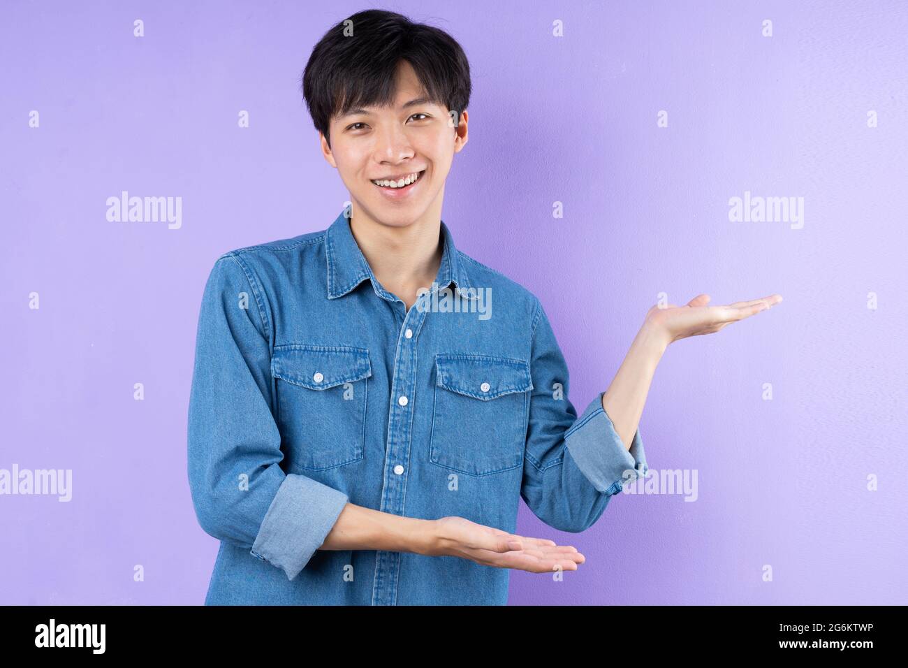 Ritratto dell'uomo asiatico in camicia blu su sfondo viola Foto Stock