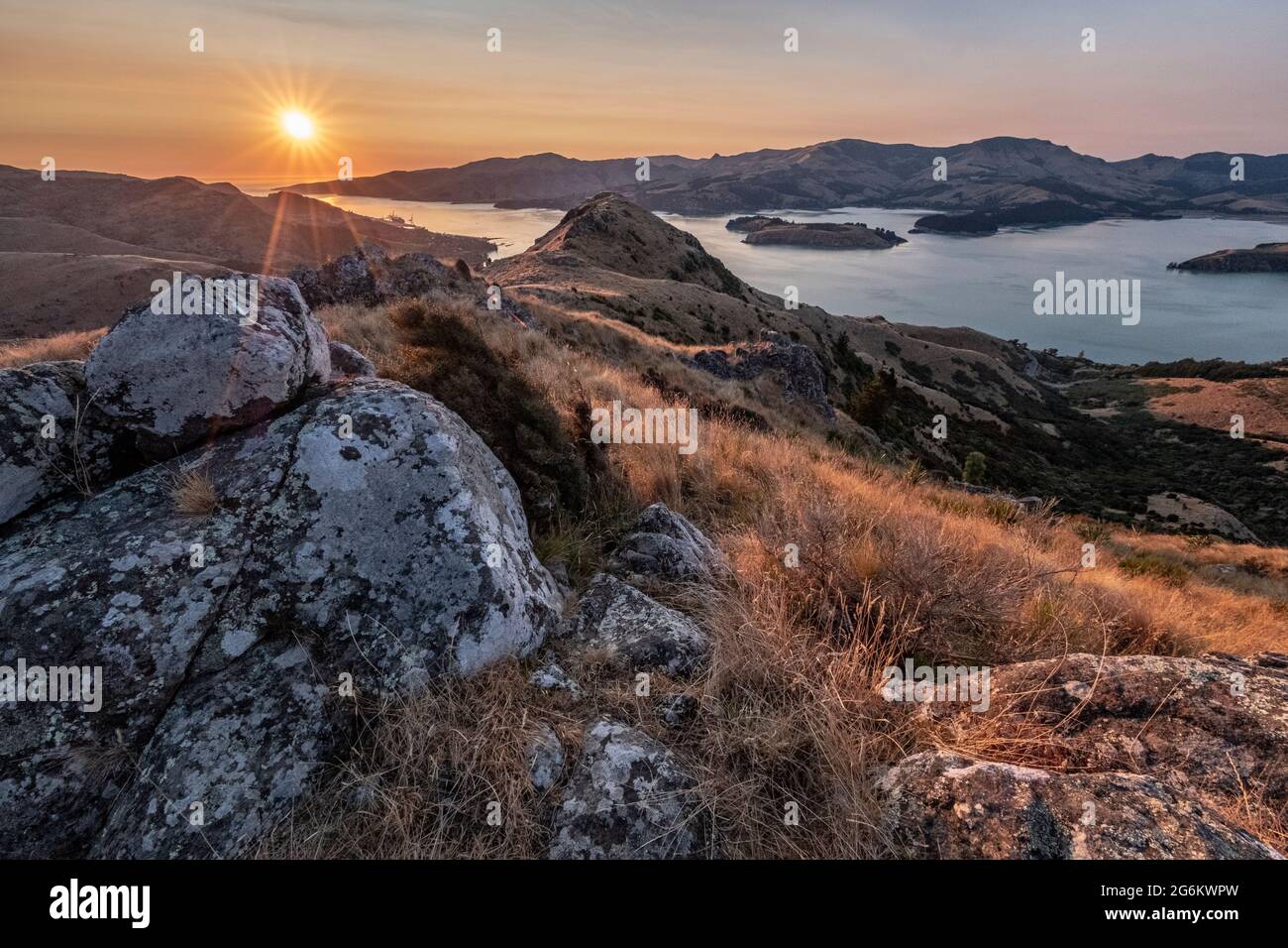 Alba su Porthills, Christchurch, Aotearoa Nuova Zelanda. Le Port Hills sono un residuo di 12 milioni di anni del cratere del vulcano Lyttelton. Vento, ra Foto Stock