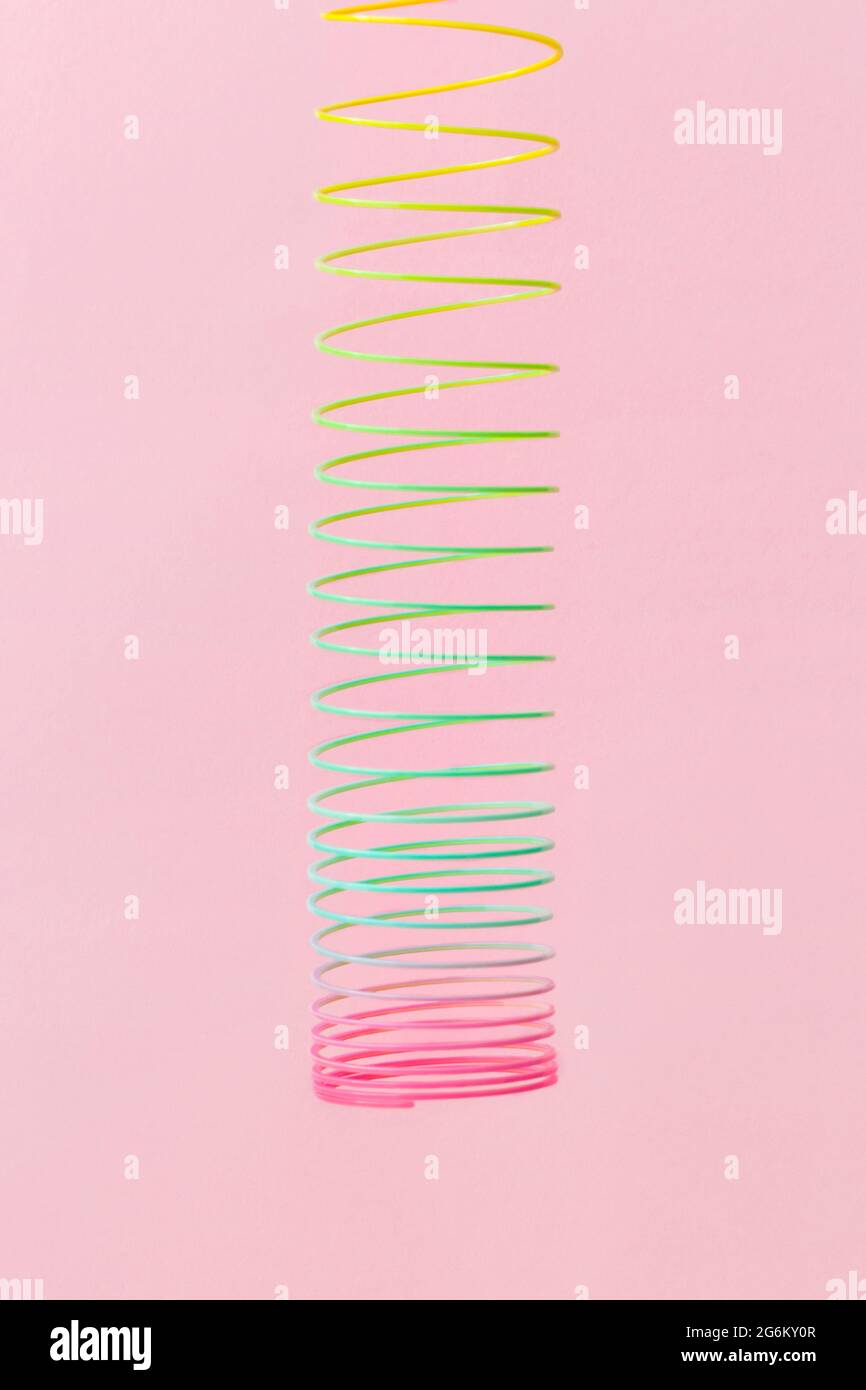 Rainbow plastica primavera giocattolo su sfondo rosa Foto Stock