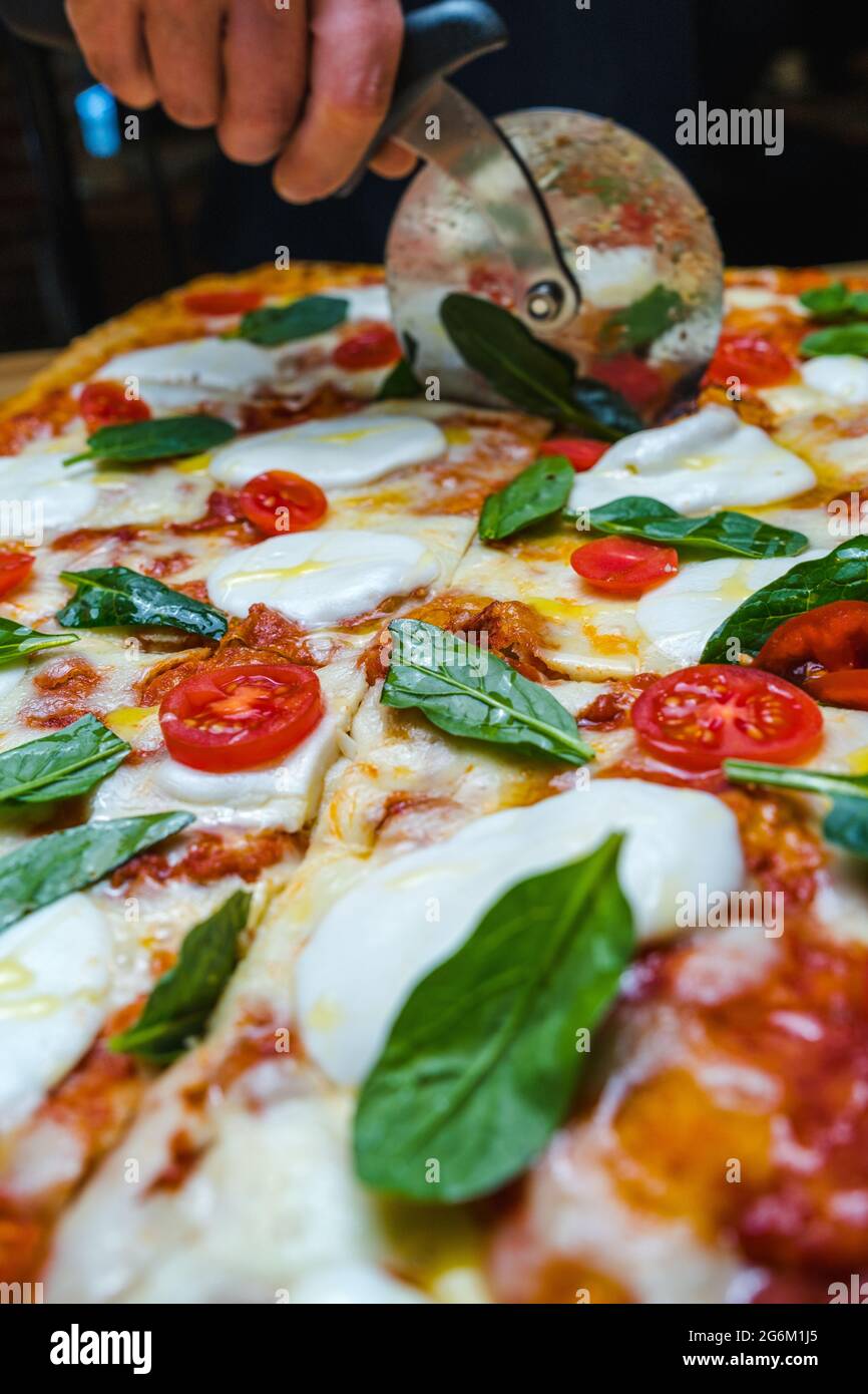 Affettare la pizza fast food con pomodori, mozzarella Foto Stock