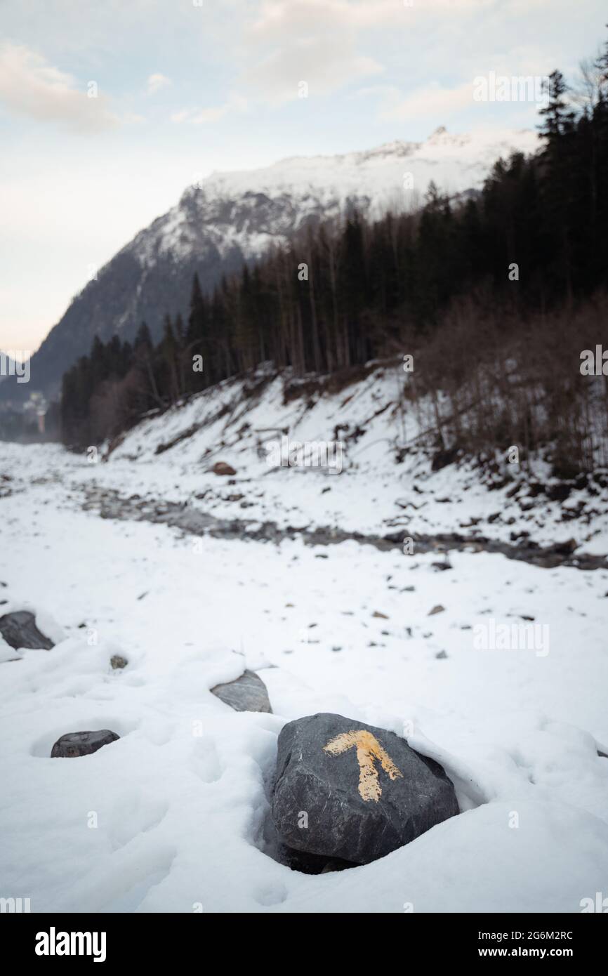 Freccia sulla pietra nelle montagne innevate. Direzione della vacanza Foto Stock