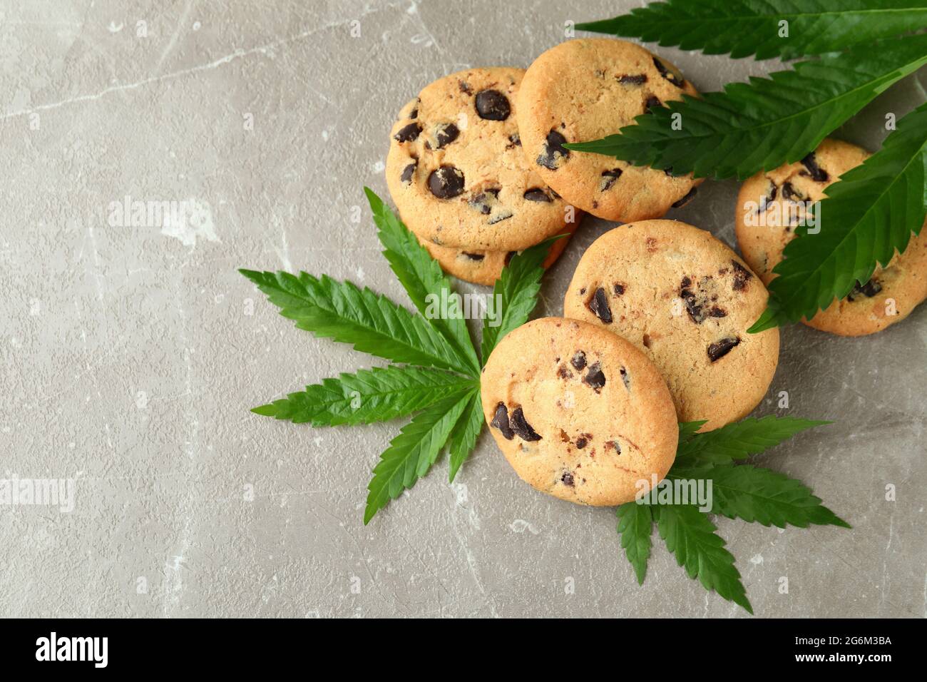 Biscotti e foglie di cannabis su tavola grigia testurizzata Foto Stock