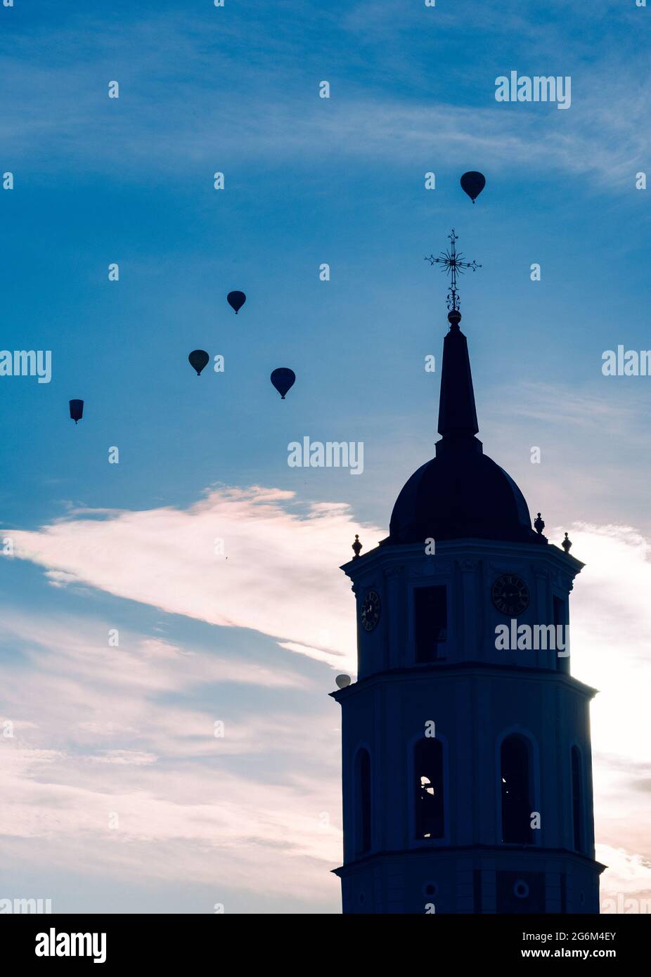 Sagoma della torre campanaria e palloncini d'aria nel cielo in serata a Vilnius, Lituania, verticale Foto Stock