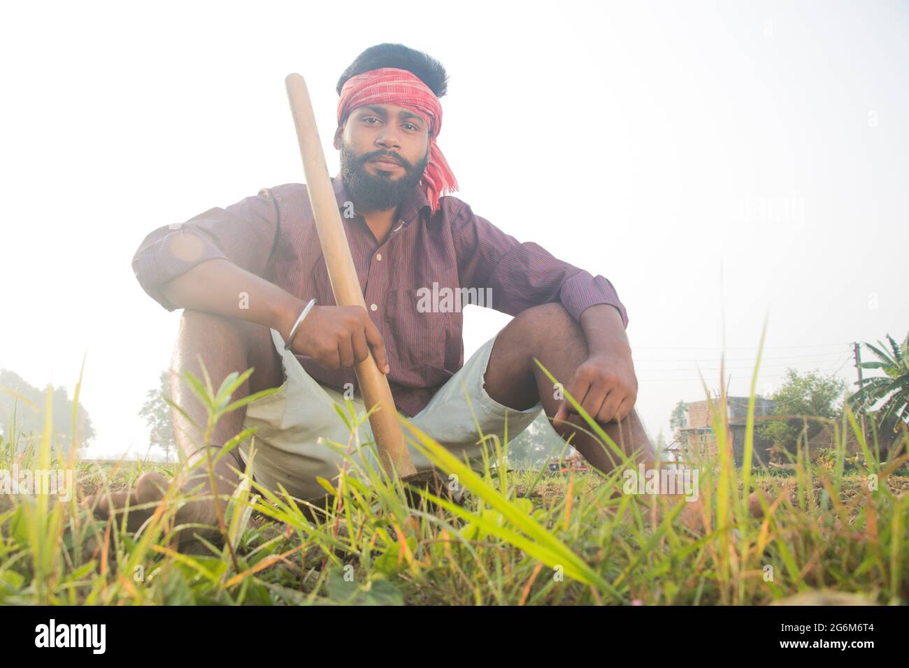 Giovane contadino rurale indiano seduto in campo agricolo Foto Stock