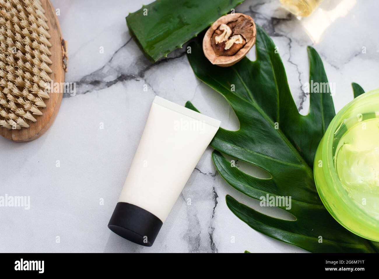 Crema viso su sfondo a foglia di palma, ingredienti naturali e sfondo di marmo. Foto Stock