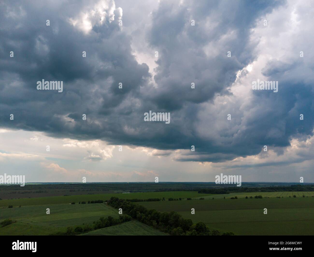 Volo aereo sopra i campi verdi con il paesaggio torbido nuvoloso. Dark piovoso scenico intenso clima estivo nella zona agricola rurale. Vista sul drone Foto Stock