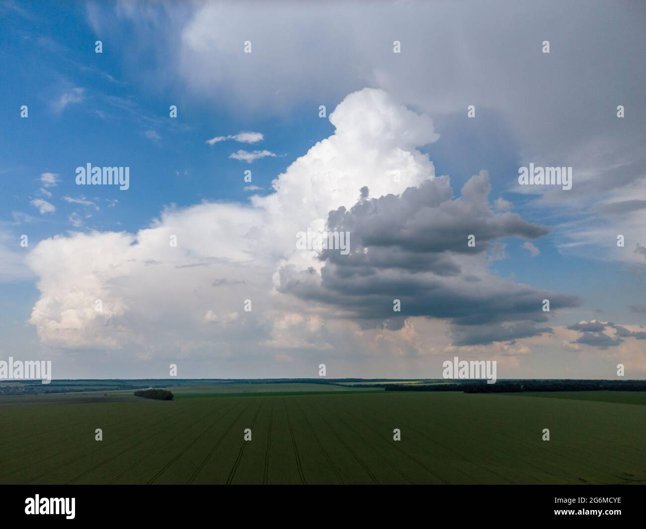 Volo aereo sopra i campi verdi con il paesaggio torbido nuvoloso su cielo blu. Dark piovoso scenico intenso clima estivo nella zona agricola rurale. Vista sul drone Foto Stock