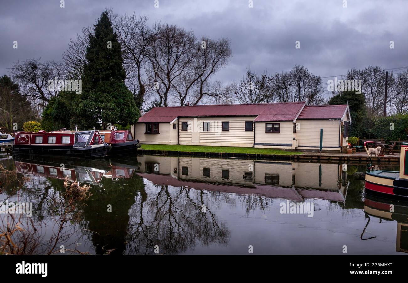 Vista delle rive del fiume Trent con barche e riflessi sulle acque del canale Erewash, durante una giornata invernale nuvolosa. Foto Stock