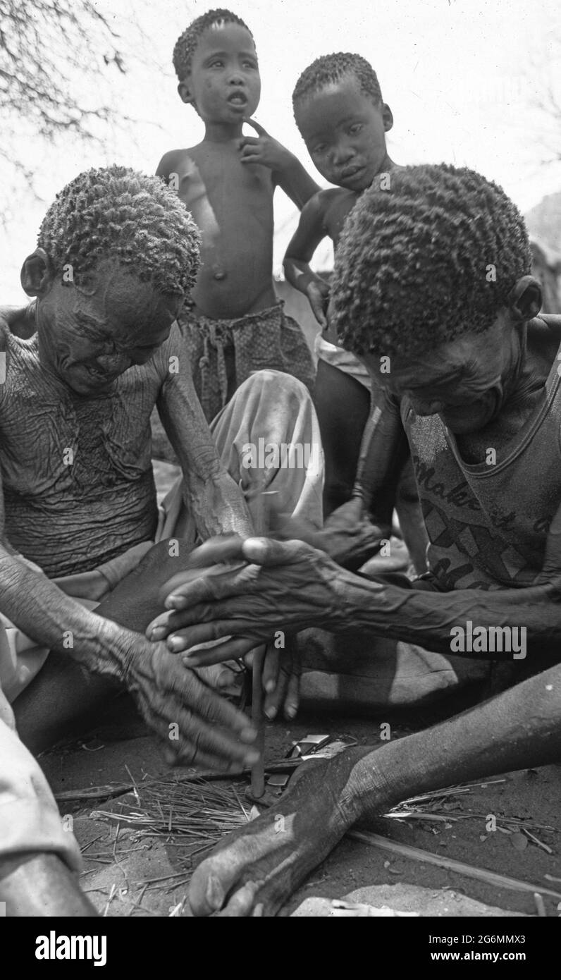 Botswana: Due cacciatori di boscimani che fanno bastoni di fuoco e legno secco nel Kalahari centrale vicino alle colline di Tsodillo Foto Stock