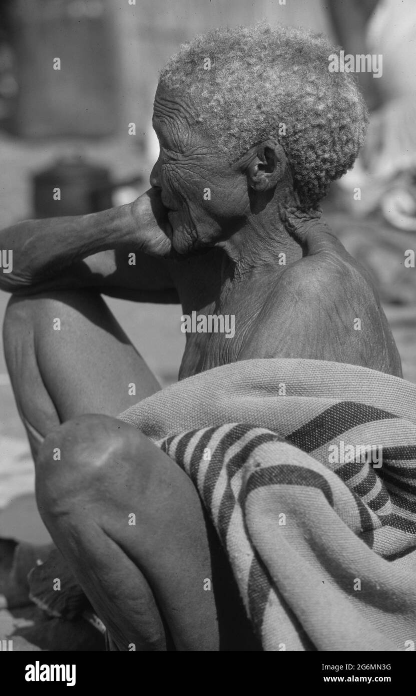 Botswana: Una vecchia san seduta nel deserto del Kalahari centrale vicino alle colline sante di Tsodillo Foto Stock