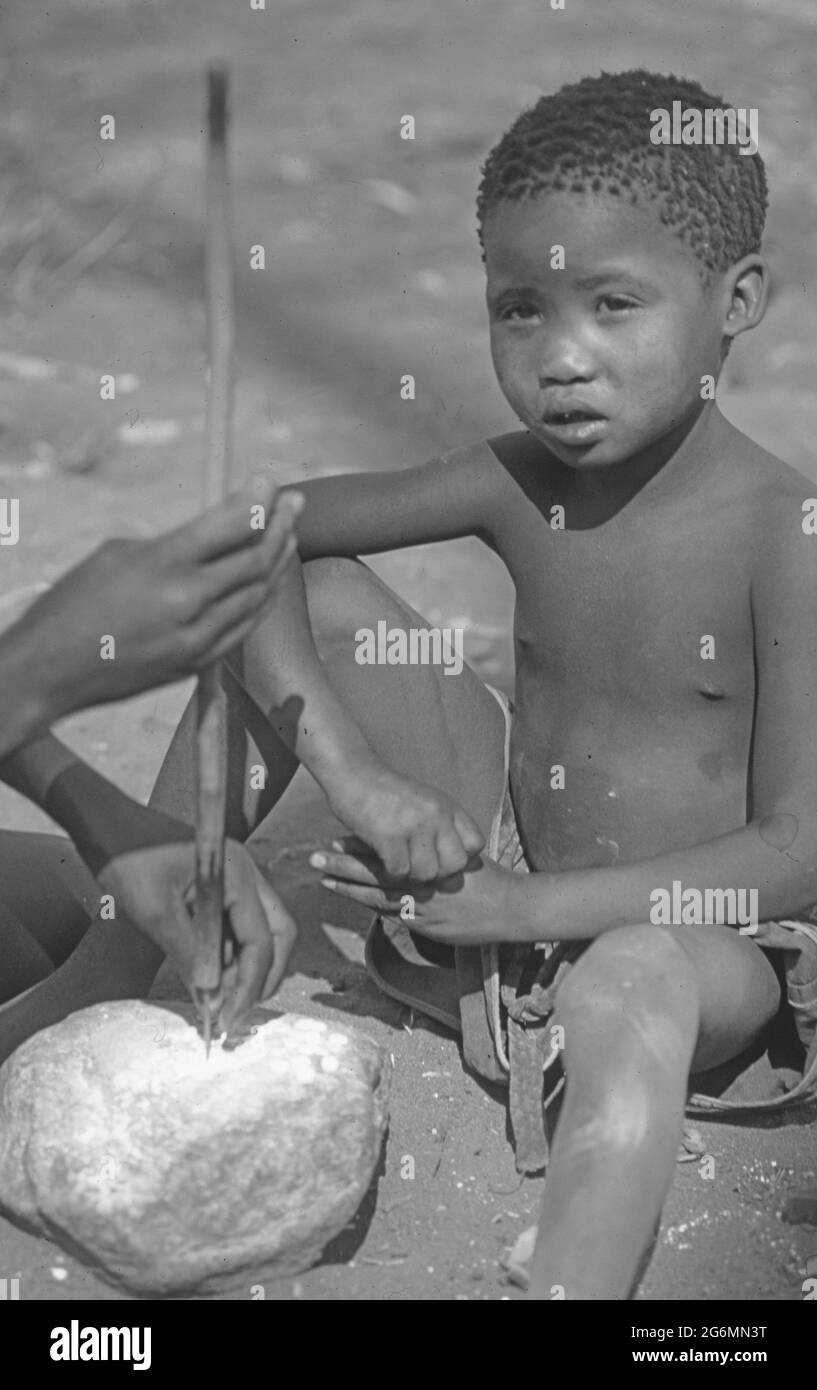 Botswana: Una donna di san con il suo bambino che crea arte boscimani da uova di struzzo Foto Stock