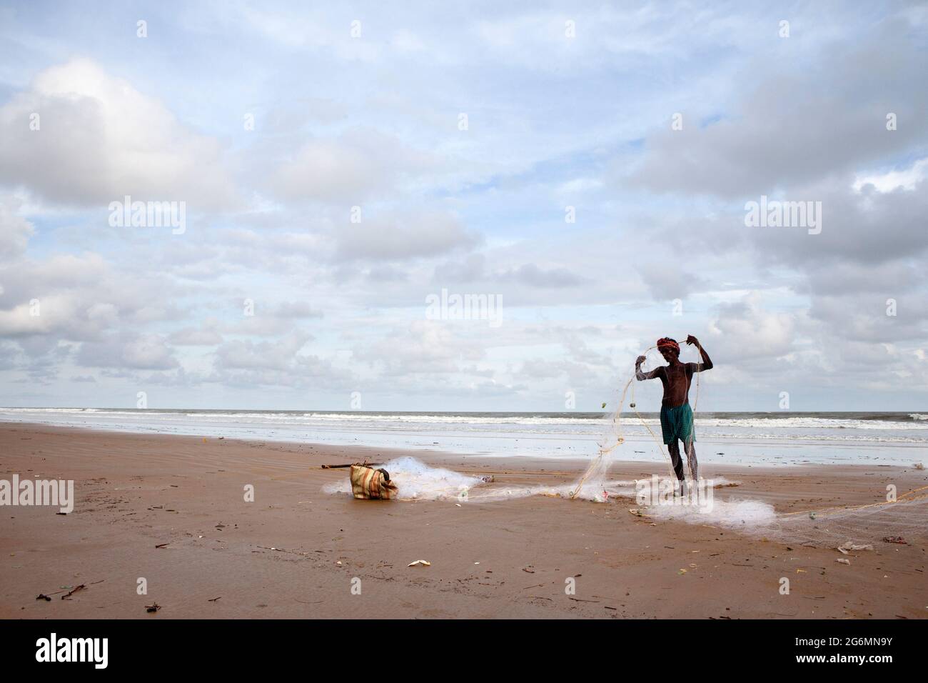 Il pescatore si prepara con la rete da pesca, in spiaggia, prima di andare in mare per la pesca. Foto Stock