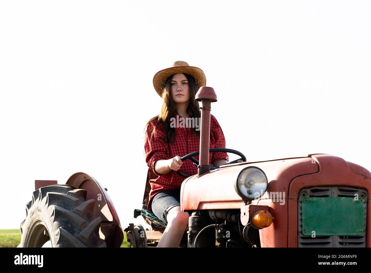 Agricoltore femminile che guida un trattore sul campo Foto Stock