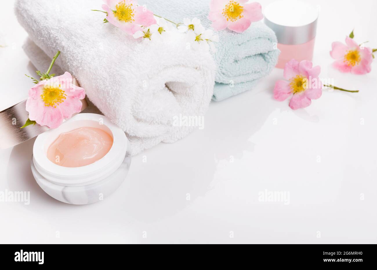 Salvietta termale bianca con rose selvatiche e crema su sfondo bianco Foto Stock