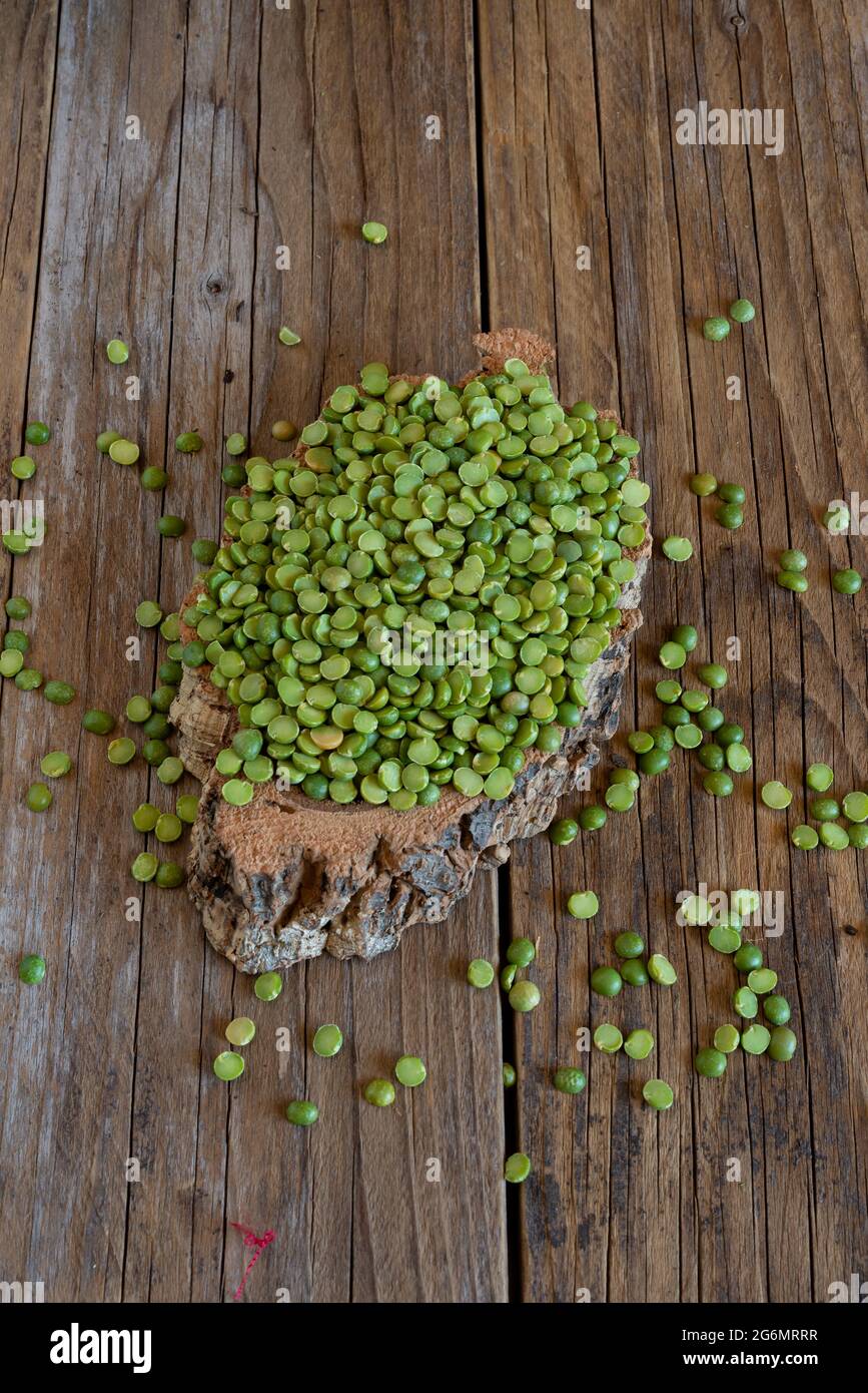 sacco di piselli verdi divisi su tavolo di legno Foto Stock