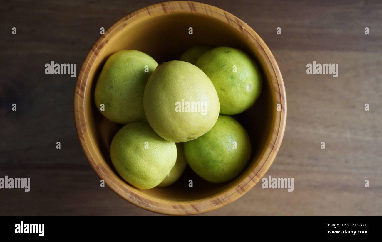 limoni verdi in una ciotola di legno . Foto Stock