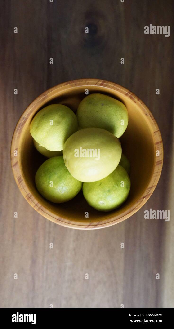 limoni verdi in una ciotola di legno . Foto Stock