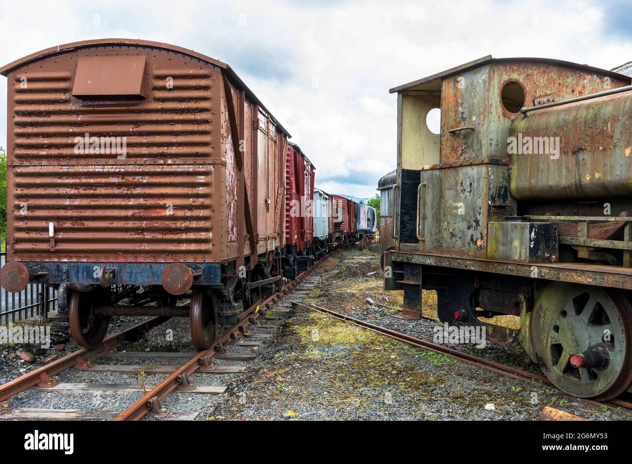 Carrozze d'epoca e parte di una locomotiva Barclay 0-4-0 con motore a canotta a sella in un siding a Dunaskin, Ayrshire, Scozia, Regno Unito Foto Stock