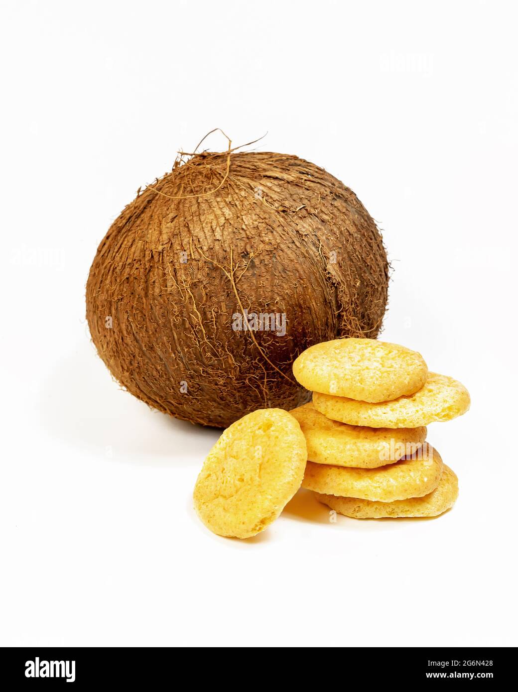 Composizione verticale con biscotti di cocco isolati, biologici e fatti in casa, con un cocco intero su sfondo bianco. Dolci con farina di cocco Foto Stock