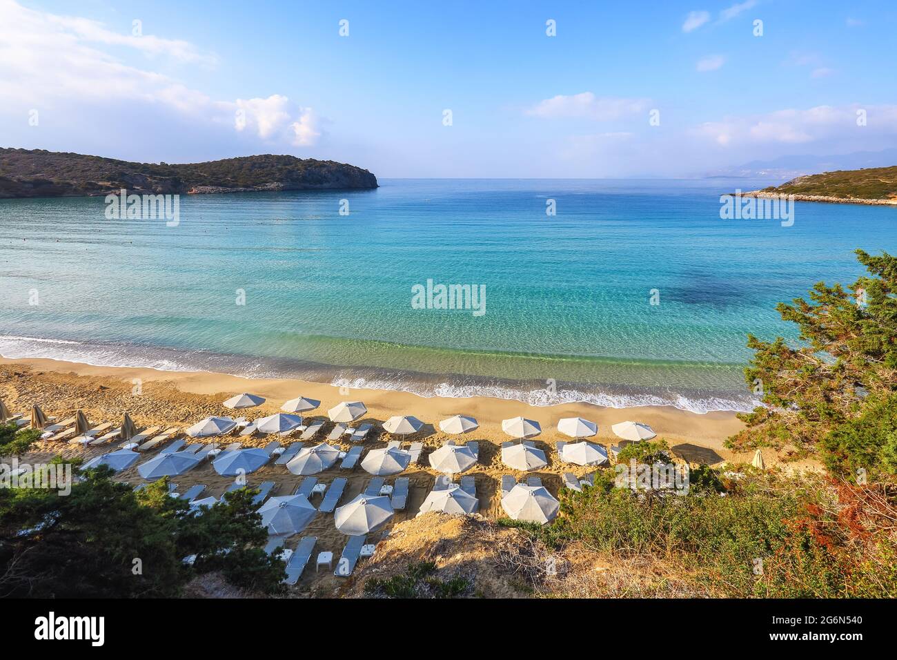 Fantastica sabbia bianca, mare e montagna. Spiaggia vuota con ombrelloni e sdraio chiusi. 2020 viaggio estivo in quarantena. Luoghi relax isola Creta, G. Foto Stock