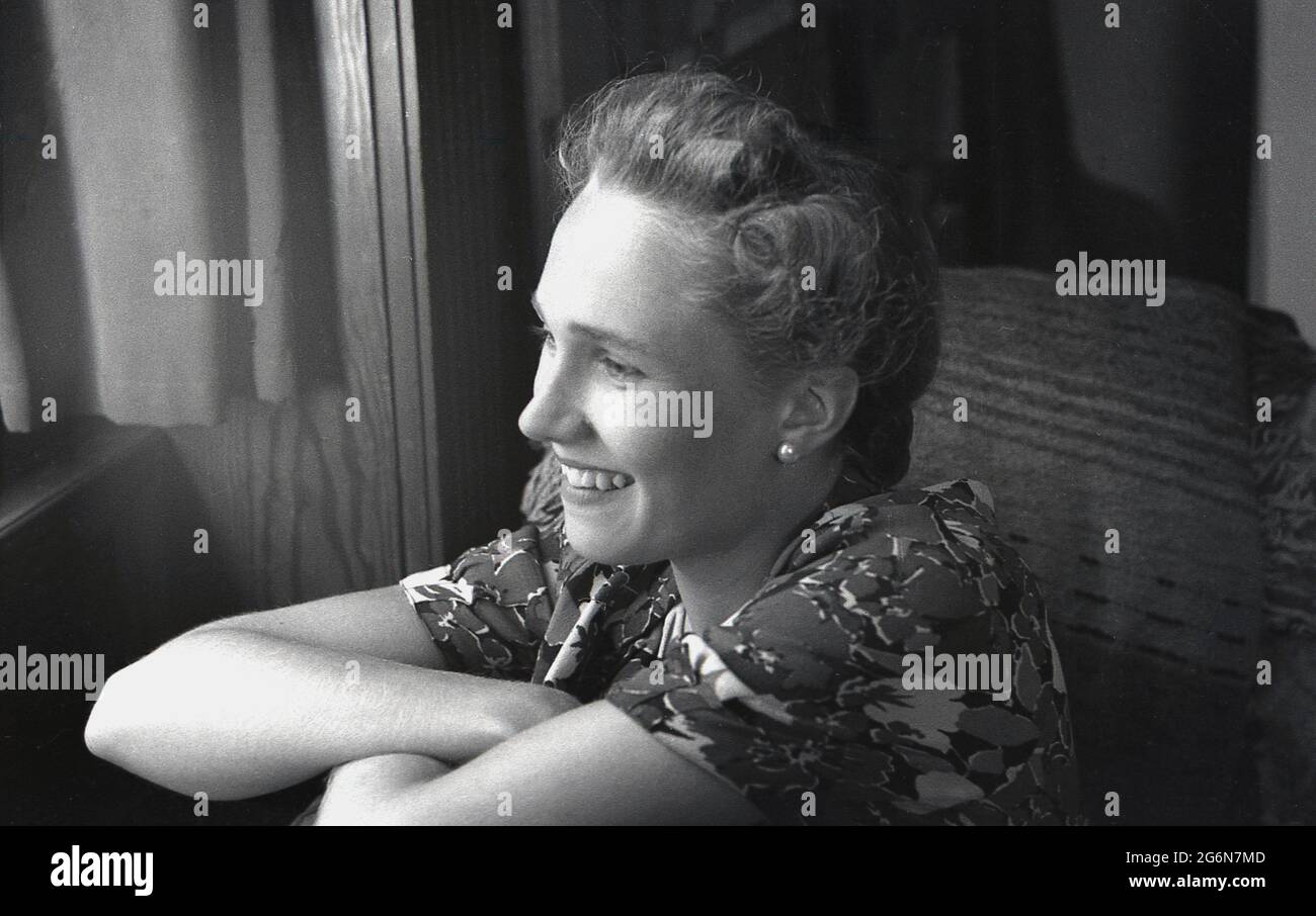 Anni '50, storico, un primo piano profilo laterale di una giovane signora inglese attraente che guarda fuori da una finestra, Inghilterra, Regno Unito. Foto Stock