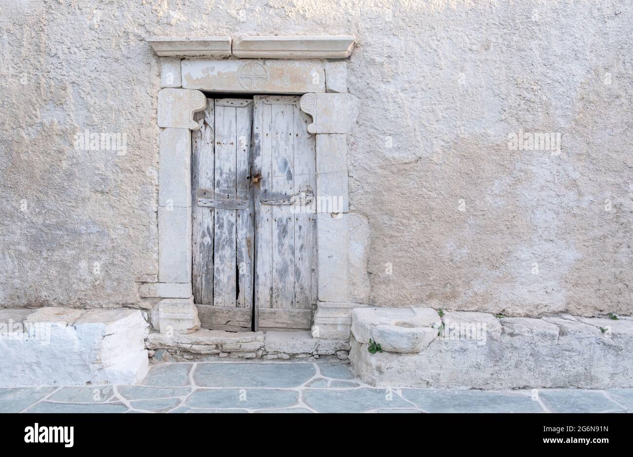 Grecia, Cicladi. Isola di FOLEGANDROS. Porta in shabby di legno con cornice in marmo, vecchia chiesa in piazza Chora. Tradizionale cappella delle Cicladi, imbiancata Foto Stock