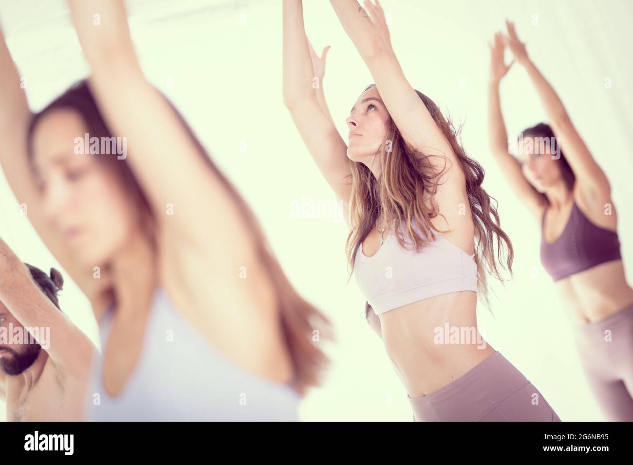 Un gruppo di giovani sportivi donne attraenti in studio di yoga, la pratica dello yoga lezione con istruttore, in piedi, stretching e rilassante dopo allenamento Foto Stock