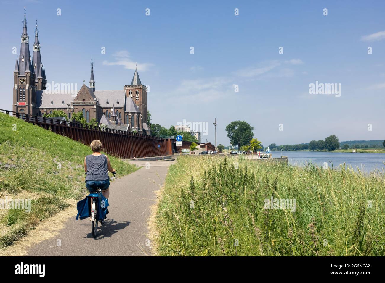 Donna in bicicletta lungo il fiume Mosa vicino al villaggio olandese Cuijk Foto Stock