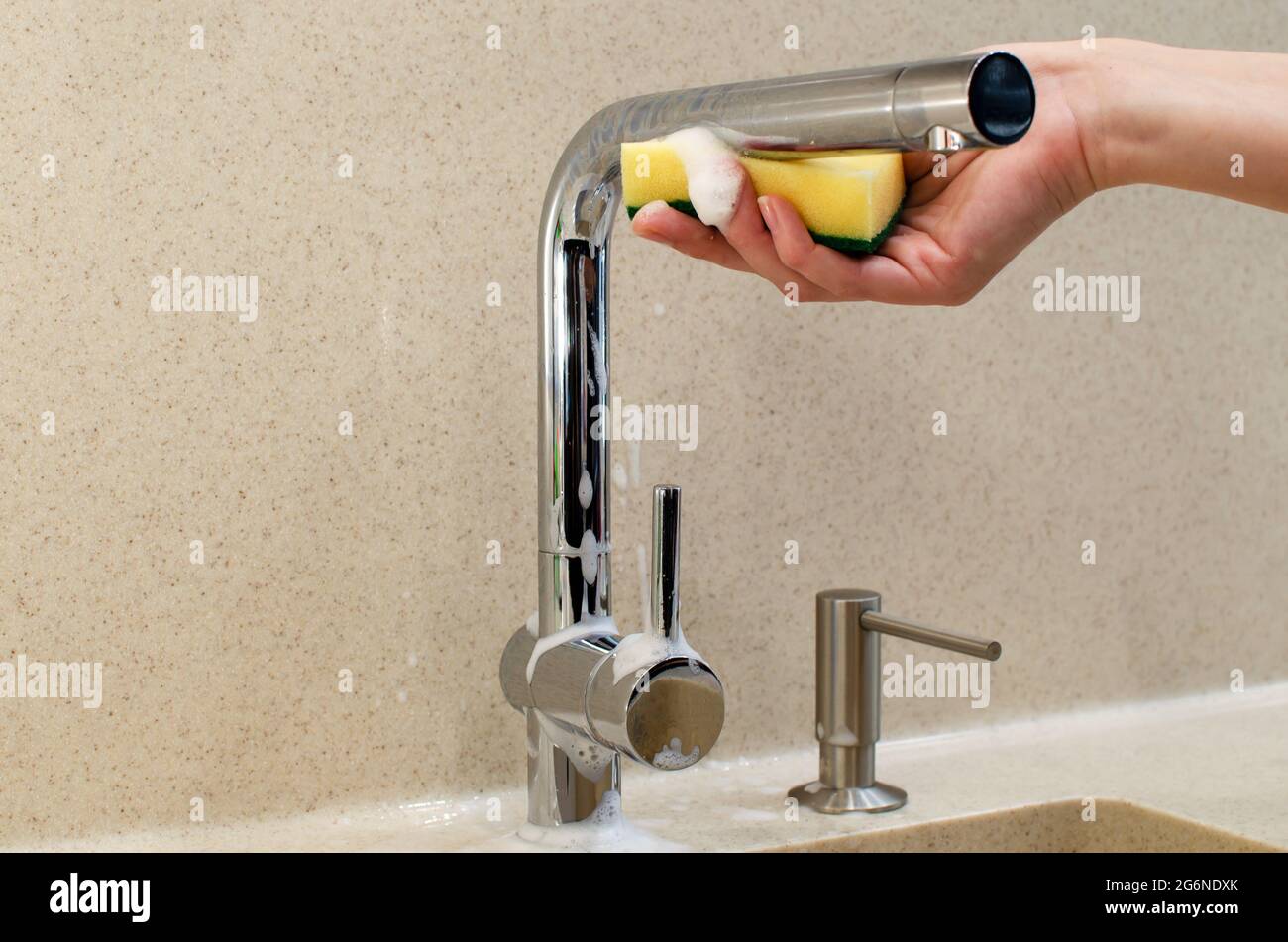 Donna lavabile a mano con rubinetto d'acqua cromato e spugna gialla nella  nuova cucina moderna. Dispenser di sapone liquido con liquido per  lavastoviglie, piano di appoggio solido Foto stock - Alamy