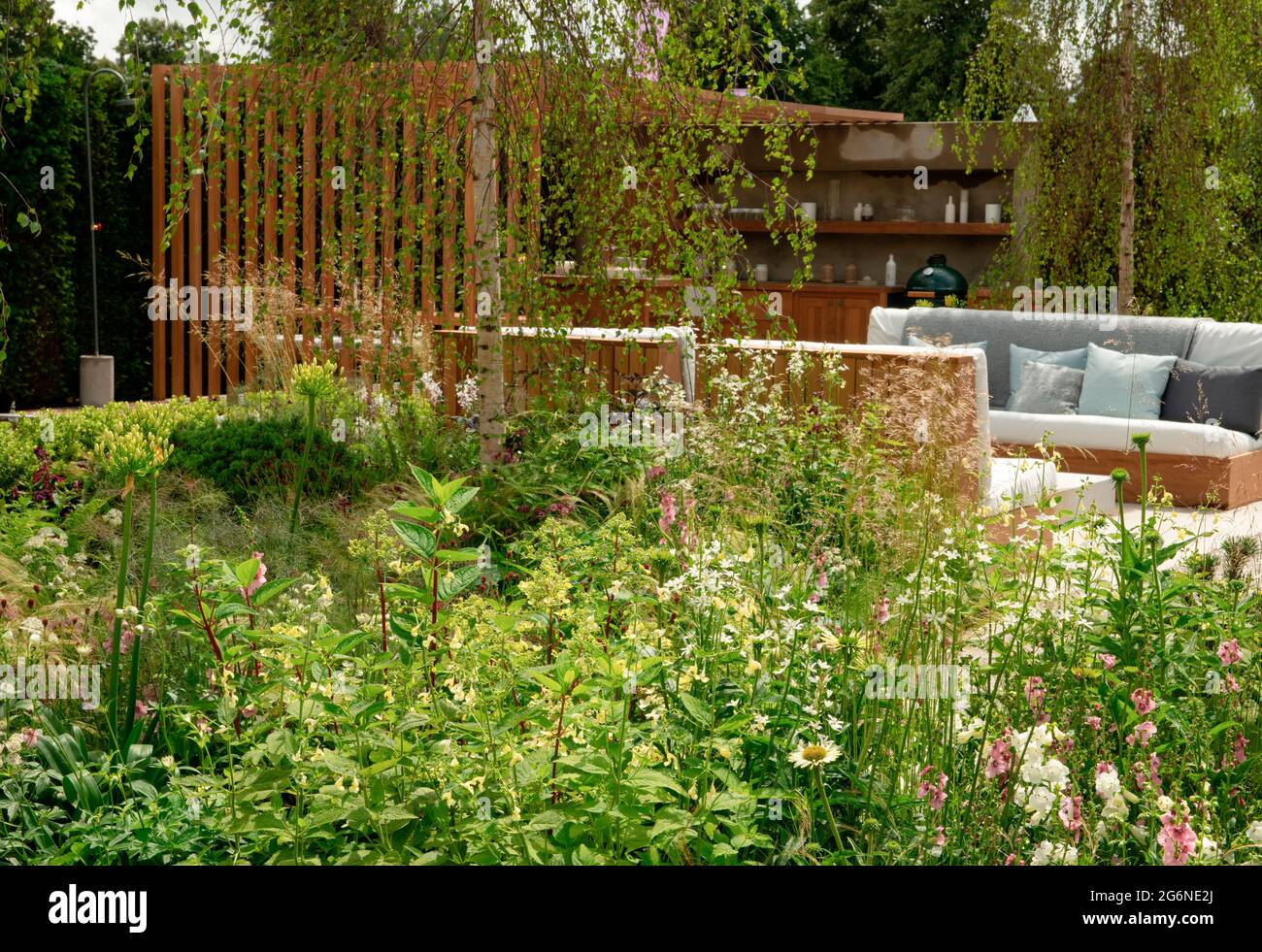 Un confine misto accanto ad un'area salotto e cucina all'aperto nel Viking Friluftsiv Garden all'Hampton Court Palace Garden Festival 2021 Foto Stock