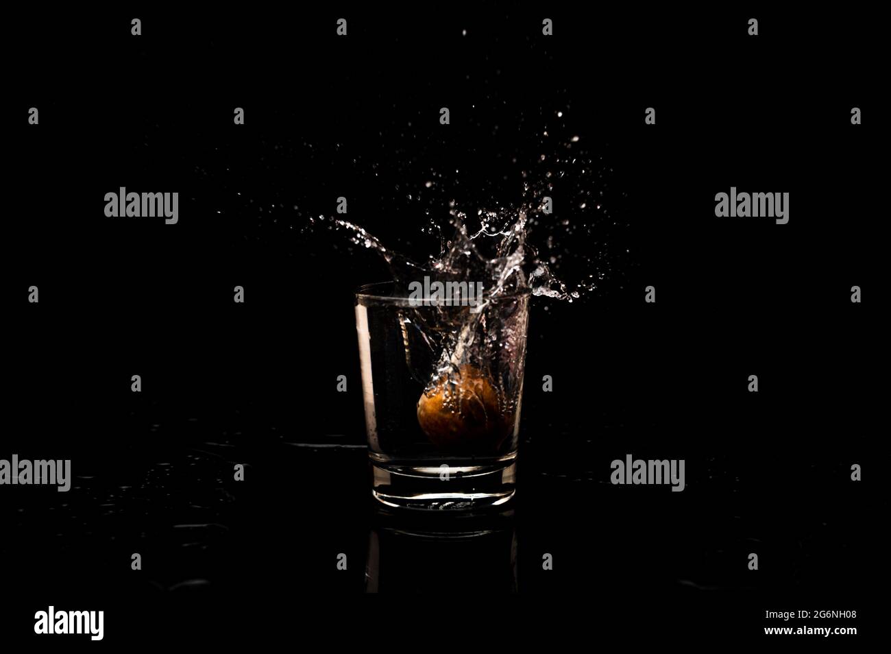 Movimento di congelamento ad alta risoluzione da un bicchiere d'acqua pulito con formazione di goccioline e bolle, isolato su sfondo nero Foto Stock