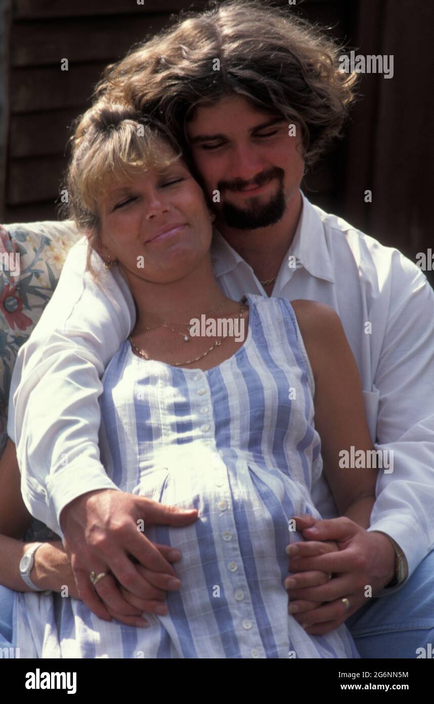 donna fortemente incinta seduta fuori con il suo partner Foto Stock