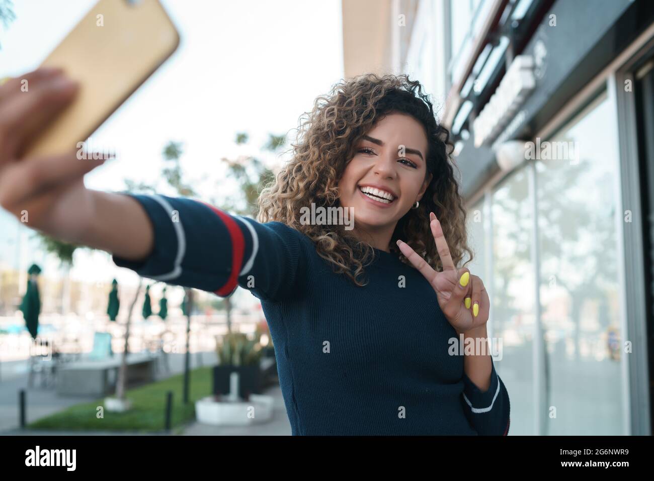 Giovane donna che prende selfie con un telefono cellulare all'aperto. Foto Stock