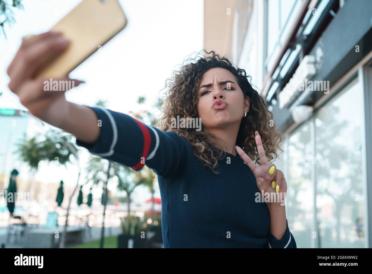 Giovane donna che prende selfie con un telefono cellulare all'aperto. Foto Stock