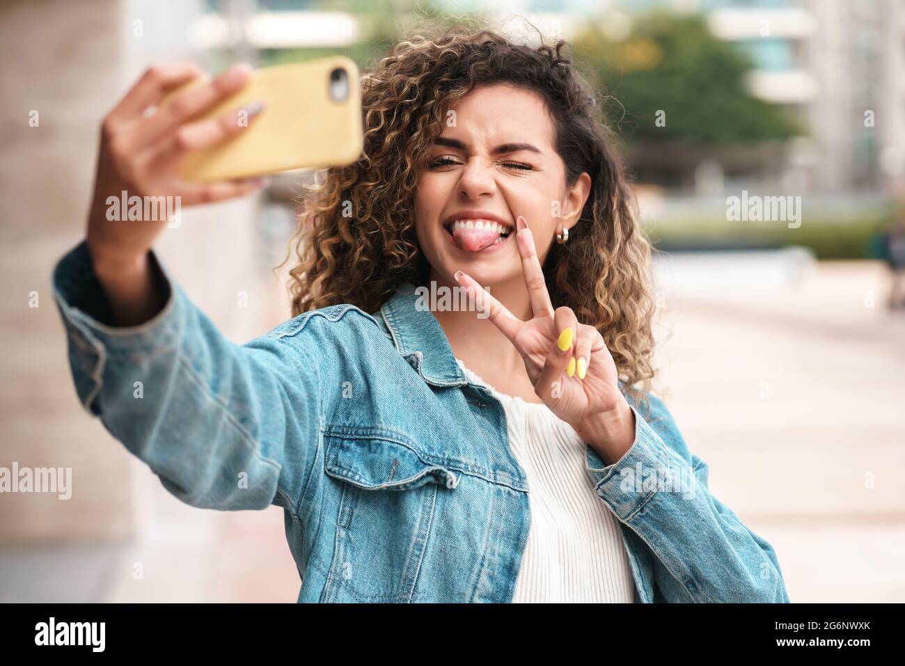 Giovane donna che prende selfie con un telefono cellulare all'aperto. Foto Stock