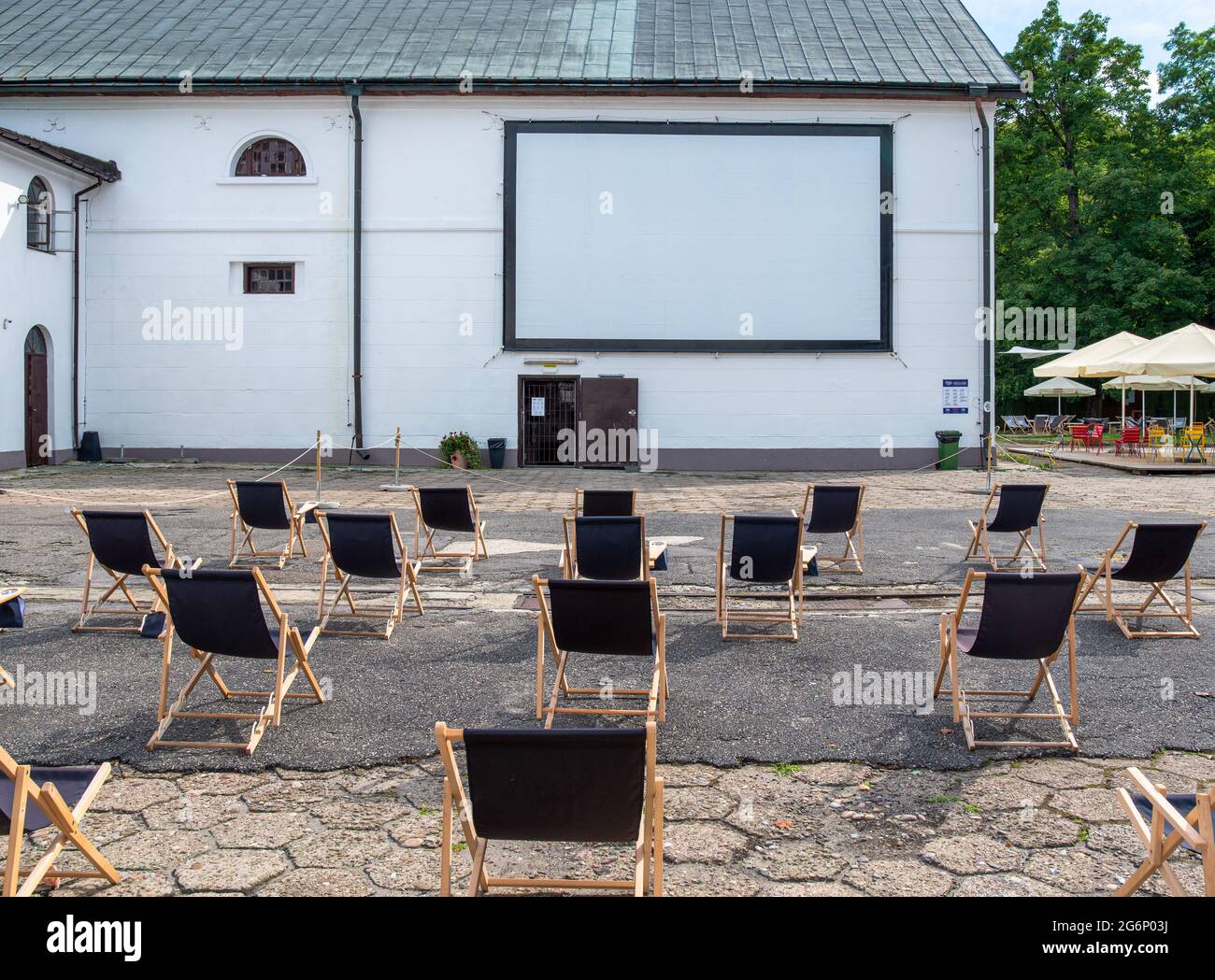 Oper-air, cinema all'aperto nel cortile della fabbrica di birra a Zwierzyniec, Polonia. File di semplici lettini neri davanti allo schermo installato sulla parete. Foto Stock