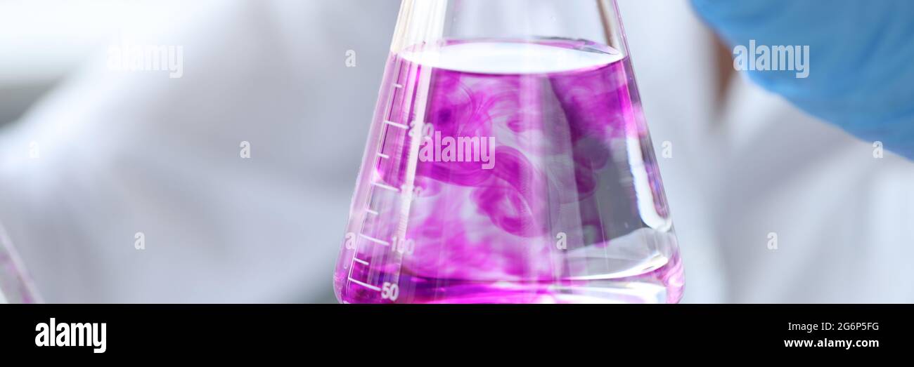L'ostruzione della provetta con il liquido rosa in mano a scienziato Foto Stock