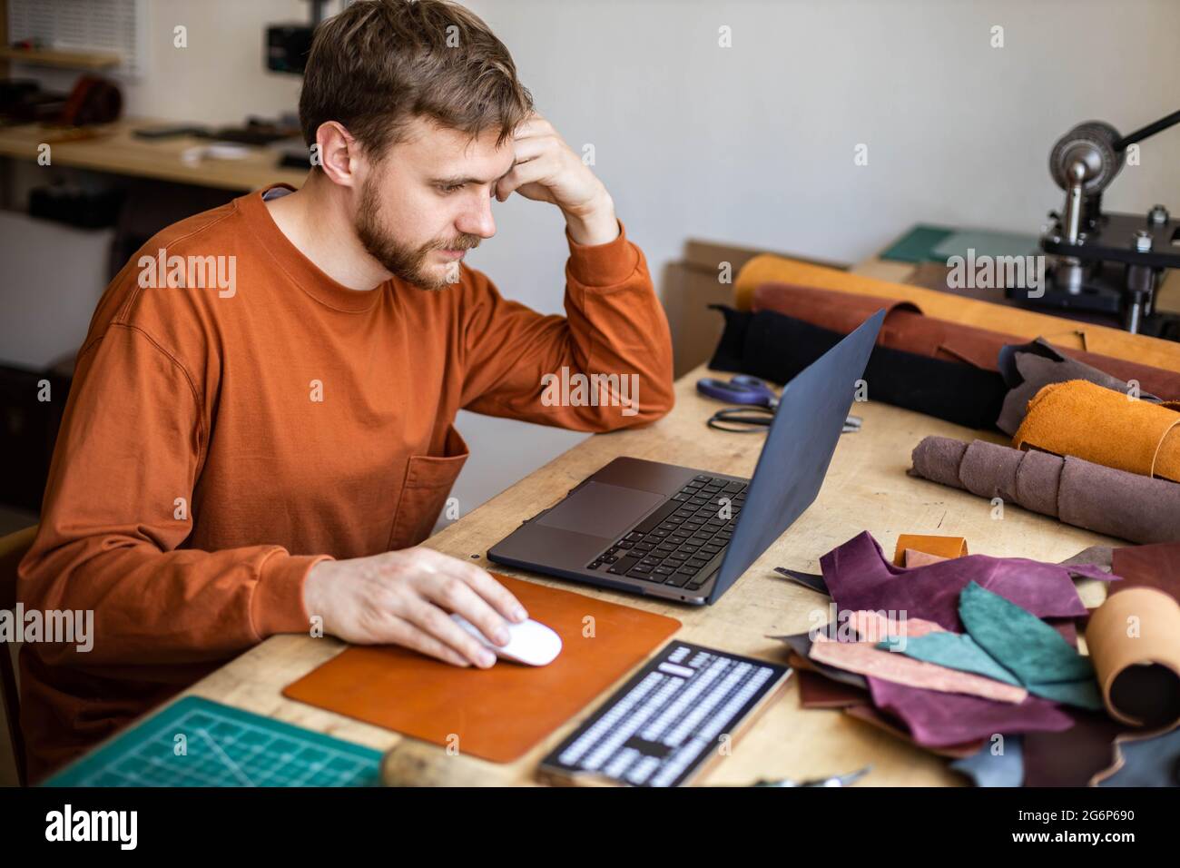 Maschio tanner lavoro uso computer portatile chatting surfing internet promozione pubblicità di leatherwork Foto Stock