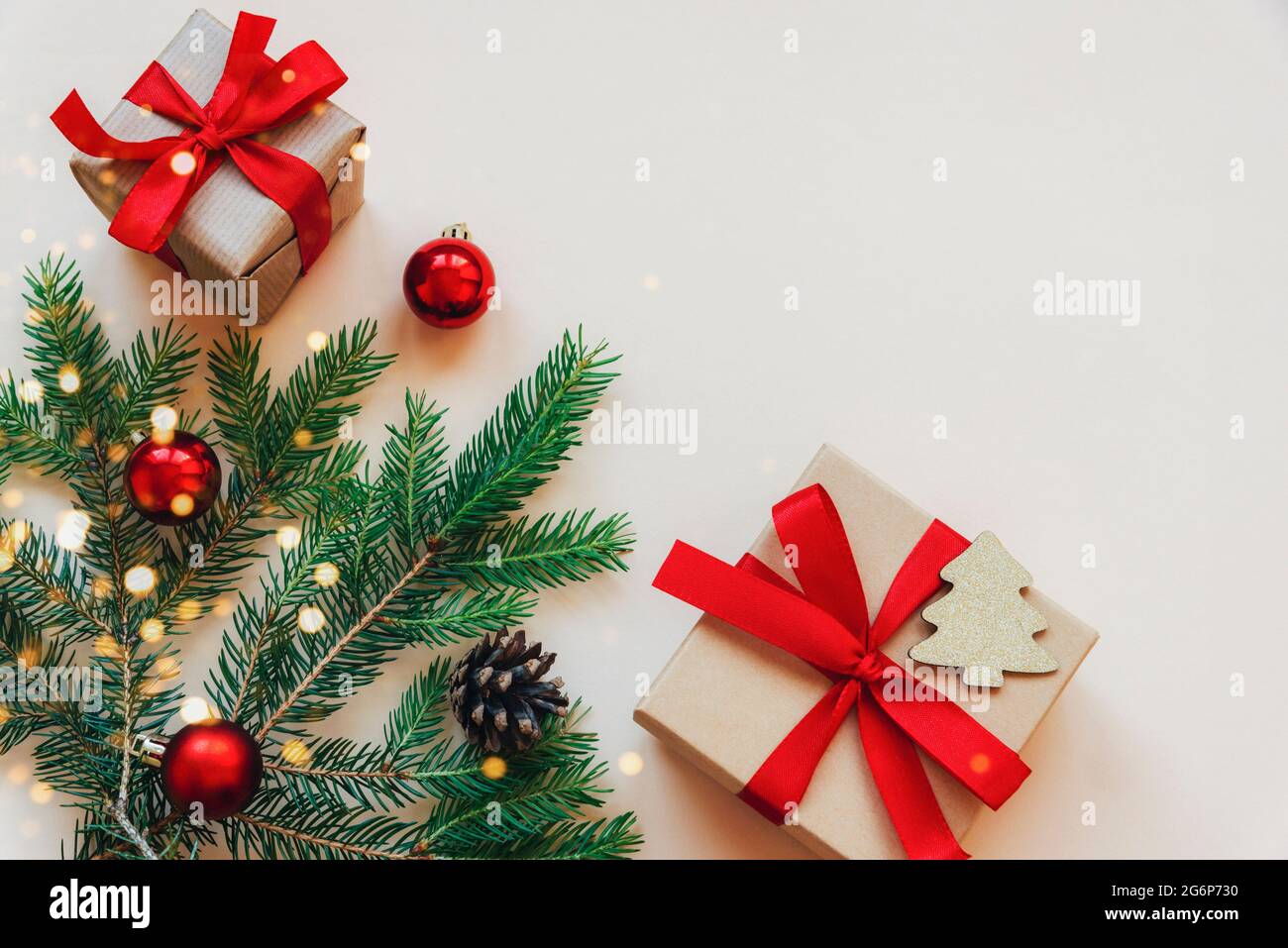 Due regali e rami di abete verde con decorazioni su sfondo beige. Concetto di Natale. Vista dall'alto, disposizione piatta, spazio per la copia Foto Stock