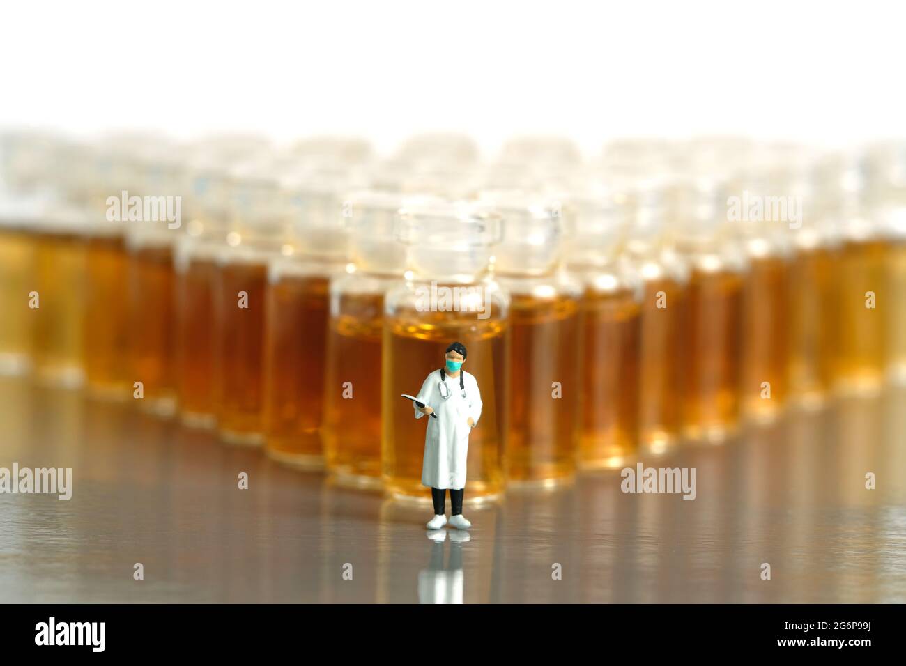 Foto di personaggi giocattolo in miniatura. Risultato del test clinico del vaccino. Un medico con tuta in piedi davanti al flaconcino della fiala. Foto immagine Foto Stock