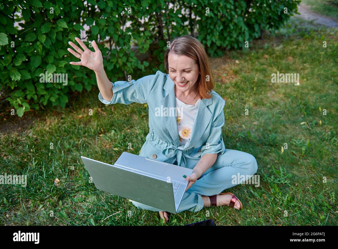 una ragazza felice con un computer portatile seduto sull'erba Foto Stock