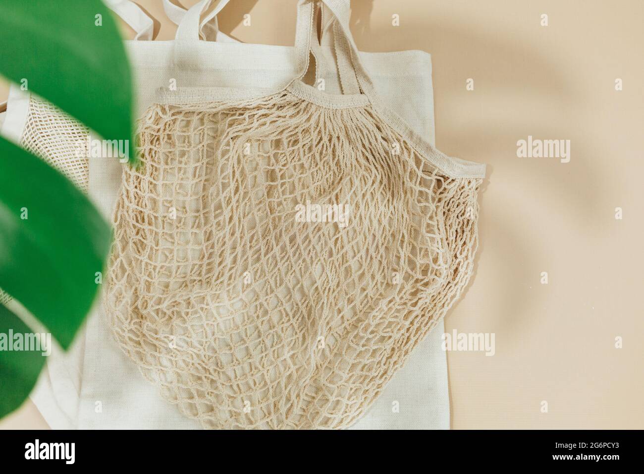 Sacchetti in rete di cotone riutilizzabili beige su sfondo beige. Borsa per la spesa ecologica. Primo piano. Zero rifiuti alimentari concetto. Sostenibile Foto Stock