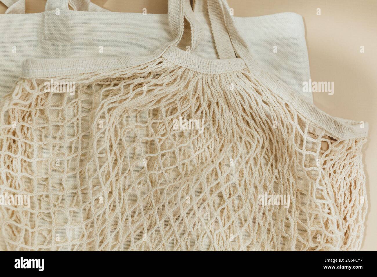 Sacchetti in rete di cotone riutilizzabili beige su sfondo beige. Borsa per la spesa ecologica. Primo piano. Zero rifiuti alimentari concetto. Sostenibile Foto Stock