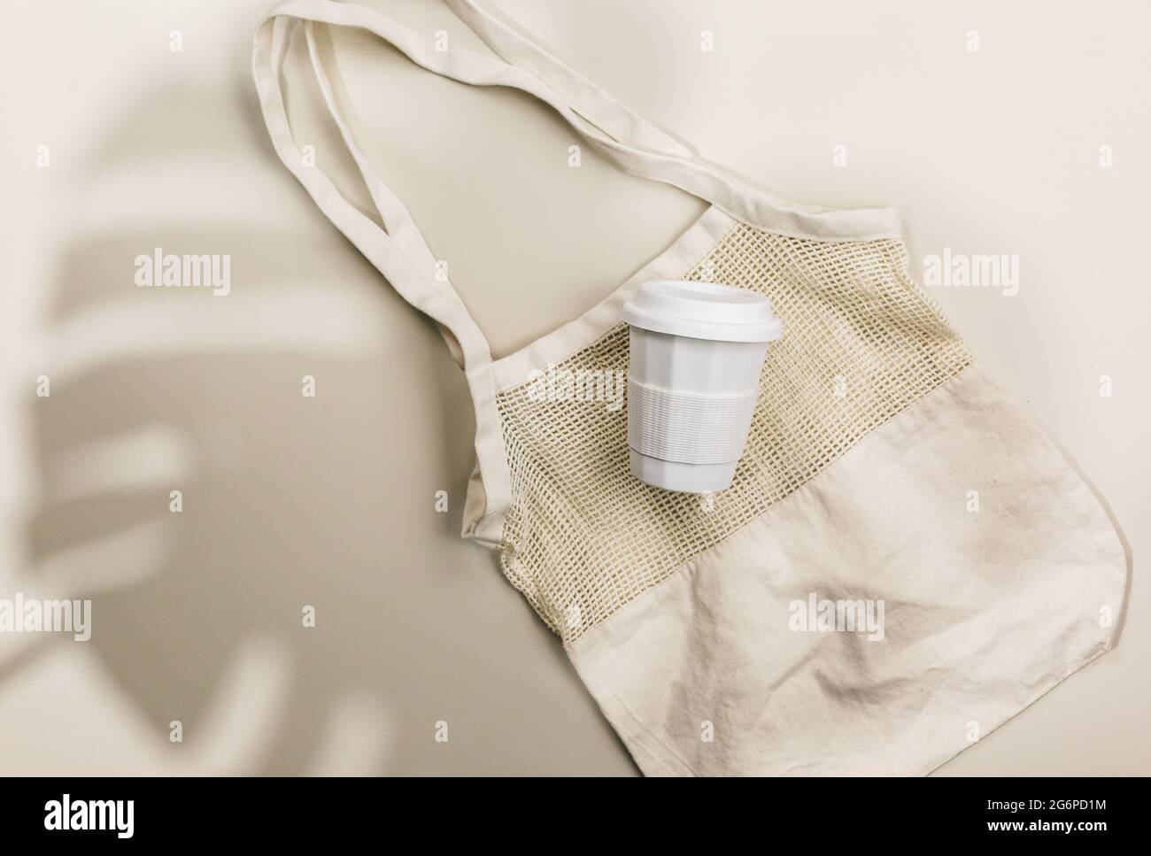 Sacchetto in rete di cotone riutilizzabile beige e tazza di caffè su sfondo beige. Borsa per la spesa ecologica. Primo piano. Zero rifiuti alimentari concetto. Vita sostenibile Foto Stock