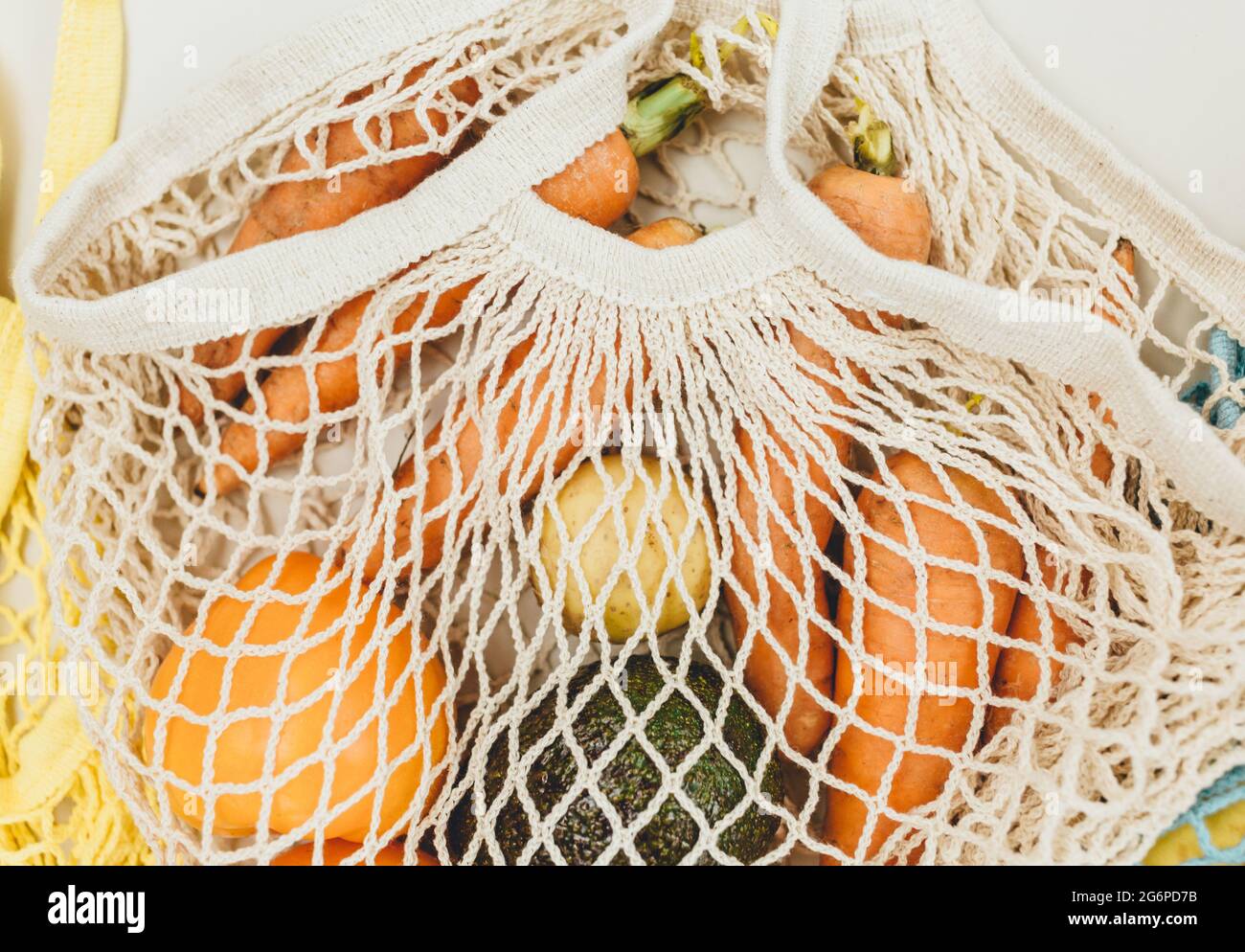 Verdure fresche in un sacchetto di maglia di cotone riutilizzabile beige su sfondo beige. Borsa per la spesa ecologica. Zero rifiuti alimentari concetto. Vita sostenibile Foto Stock