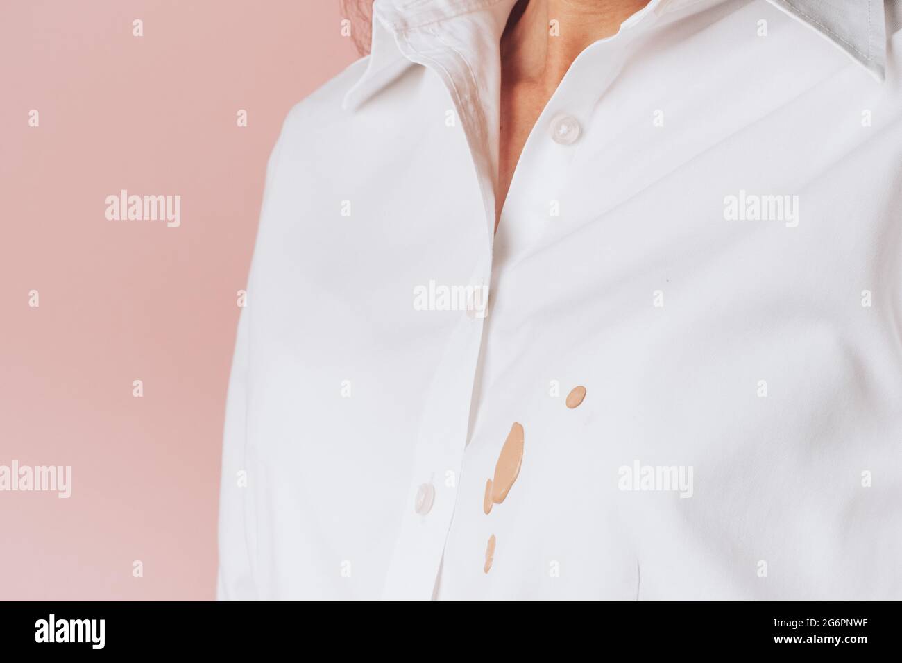 Prodotti cosmetici fuoriuscite su abbigliamento da donna, isolati su sfondo rosa. Foto di alta qualità Foto Stock